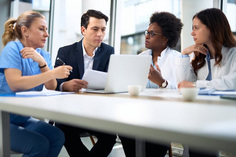 Mid adult businessman working on laptop during a meeting with medical experts